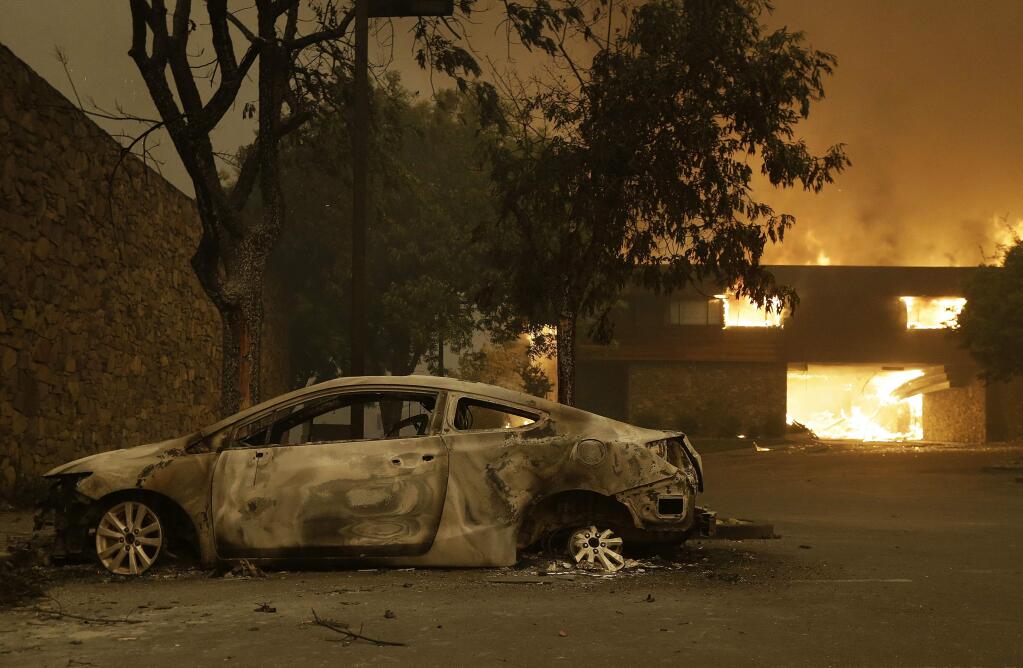 The remains of a car sits near the Fountaingrove Inn Hotel as it burns at rear in Santa Rosa, Calif., Monday, Oct. 9, 2017. (AP Photo/Jeff Chiu)