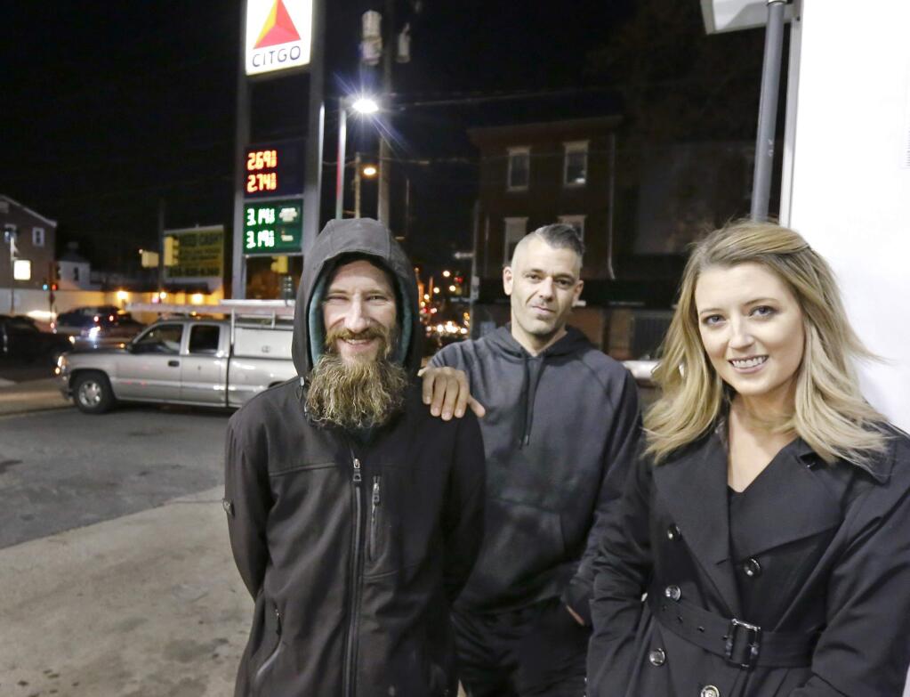 In this Nov. 17, 2017 photo, Johnny Bobbitt Jr., left, Kate McClure, right, and McClure's boyfriend Mark D'Amico pose at a CITGO station in Philadelphia. When McClure ran out of gas, Bobbitt, who is homeless, gave his last $20 to buy gas for her. McClure started a Gofundme.com campaign for Bobbitt that has raised more than $13,000. (Elizabeth Robertson/The Philadelphia Inquirer via AP)