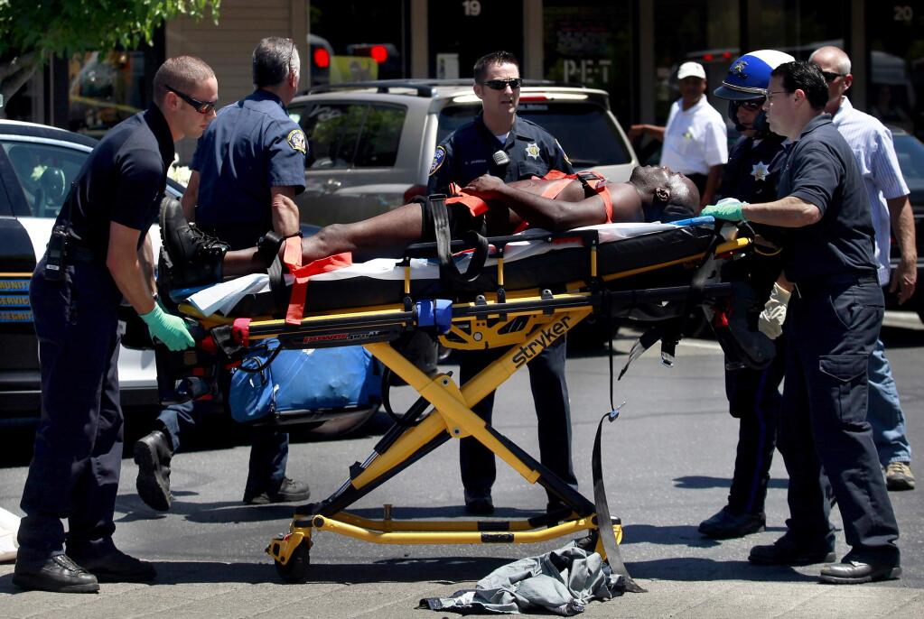 A suspect is taken by ambulance after a robbery at Bennett Valley Jewelers in Santa Rosa, Thursday, July 10, 2014. (Beth Schlanker / The Press Democrat)