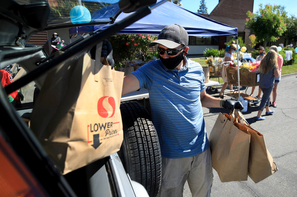 Steve Stiles places groceries in to a vehicle during a food giveaway at Elisha's Pantry in Santa Rosa, Thursday, July 30, 2020. (Kent Porter / The Press Democrat) 2020