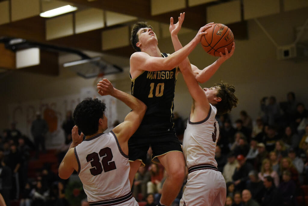 Finn Grace, center, of Windsor High going over Pedro Diaz, left, and Sam Vanden Heuvel of Healdsburg High during the final minutes of the Redwood Empire Invitational Basketball Tournament with a Windsor win of 63-42, held in Healdsburg, Calif. on Friday, Dec. 9, 2022. (Erik Castro / For The Press Democrat)