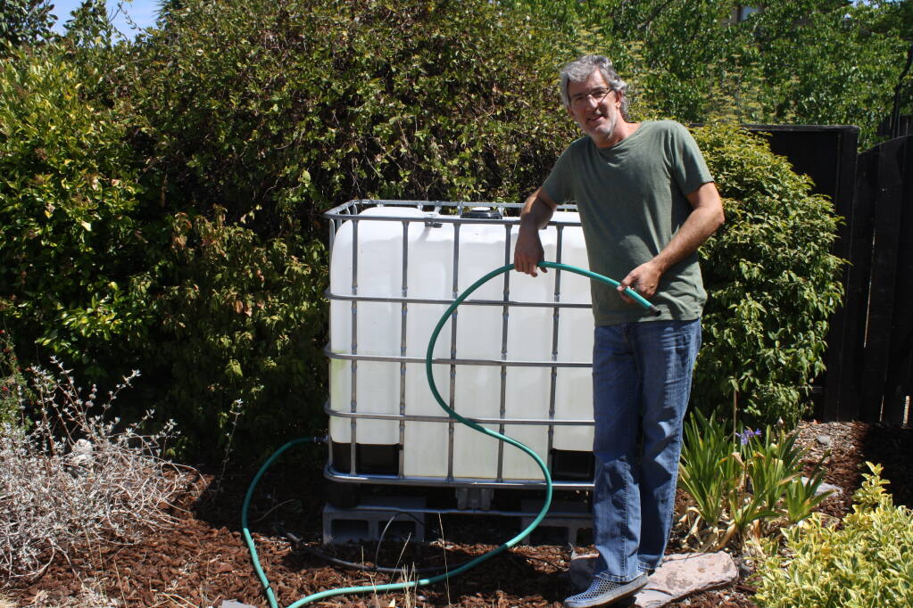 Patrick Ronsche stands next to a water tank at his Healdsburg home near Simi Winery. He uses it store free recycled water delivered by city of Healdsburg contract water truck haulers once a week. He uses the water to restore a small front lawn and plants in the yard. Some 700 Healdsburg residents have signed up for this program reducing the need for potable water by 54%. (Gary Quackenbush / for North Bay Business Journal)