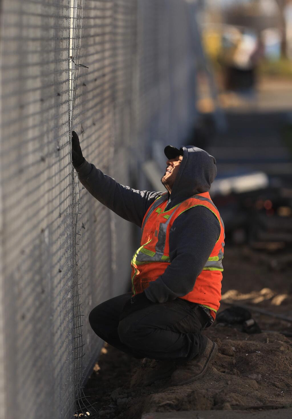 A worker from Hadrian Construction Company looks through a gap in a new soundwall, Friday, Feb. 22, 2019 in Coffey Park, replacing the old walls that were torn down due to Tubbs fire damage in 2017. (Kent Porter / Press Democrat) 2019