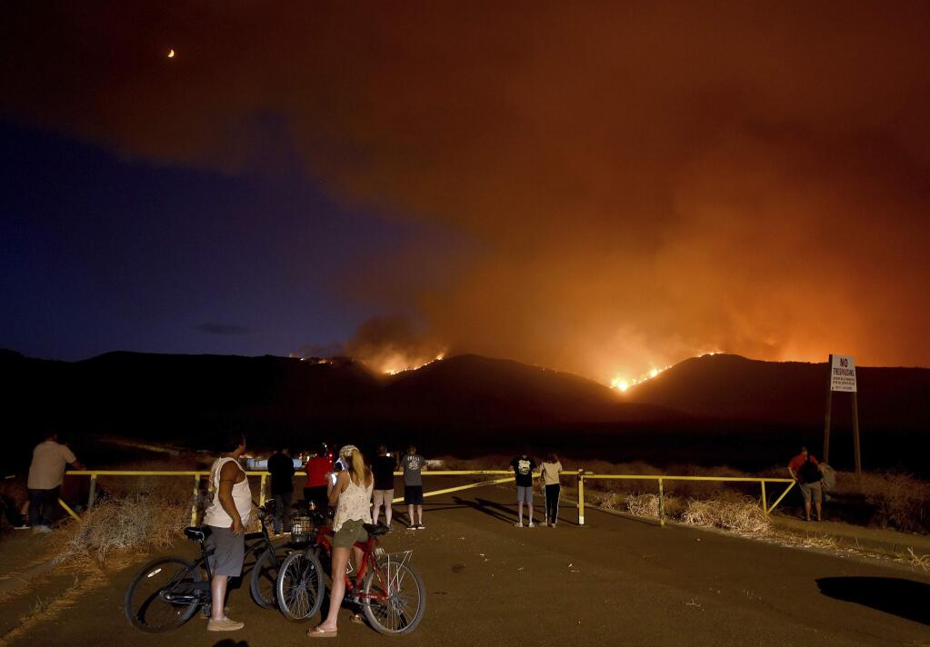 In this Wednesday evening, Sept 4, 2019 photo, residents and onlookers watch as the Tenaja fire burns in and above Cole Canyon at the top of Vineyard Parkway in Murrieta, Calif. (Will Lester/The Orange County Register via AP)
