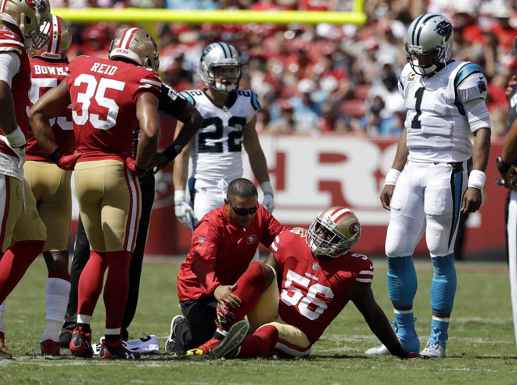 San Francisco 49ers linebacker Reuben Foster is tended to by a trainer as teammates and Carolina Panthers quarterback Cam Newton watch during the first half in Santa Clara, Sunday, Sept. 10, 2017. (AP Photo/Marcio Jose Sanchez)