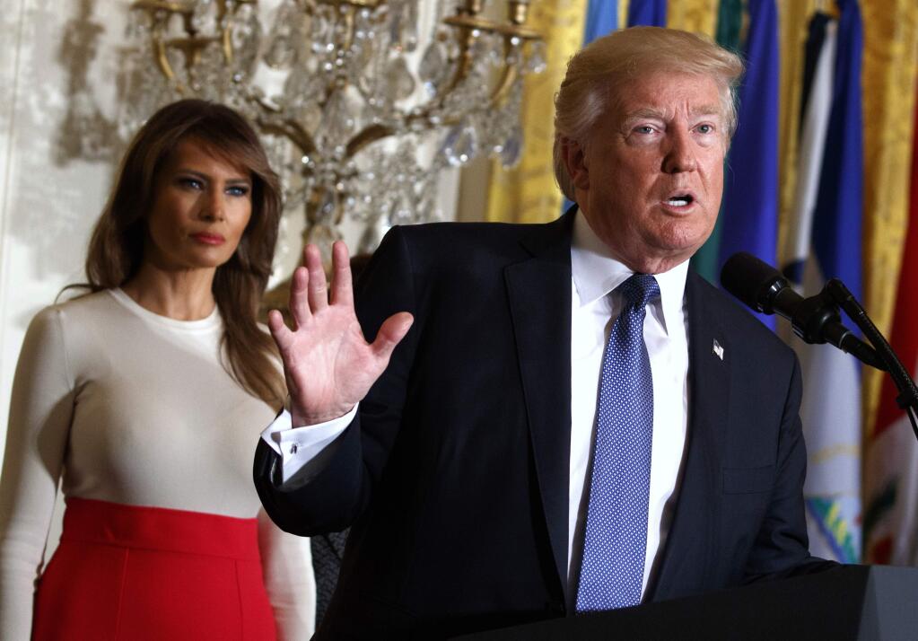 FILE - In this Friday, Oct. 6, 2017, file photo, President Donald Trump speaks during an event at the White House in Washington, as first lady Melania Trump listens. Trump's plan to combat opioid drug addiction calls for stiffer penalties for drug traffickers, including the death penalty where it's appropriate under current law. The president is scheduled to unveil his plan Monday, March 19, 2018, in New Hampshire, a state hard-hit by the crisis. He'll be accompanied by first lady Melania Trump, who has shown an interest in the issue, particularly as it pertains to children. (AP Photo/Evan Vucci, File)