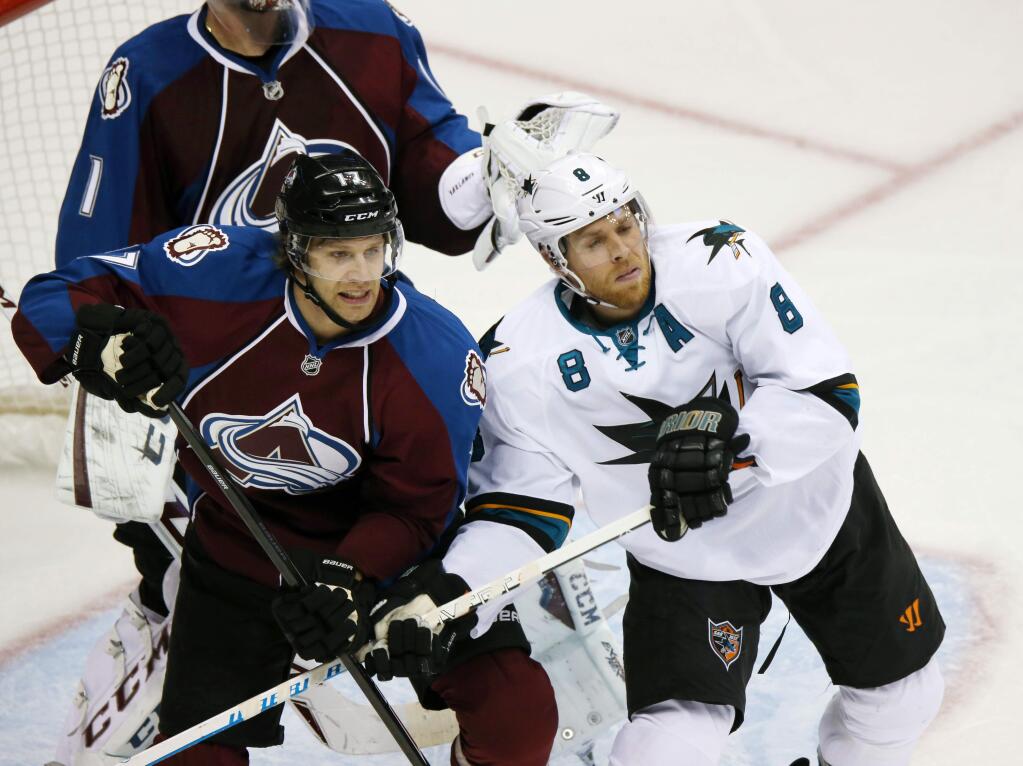 Colorado Avalanche defenseman Brad Stuart, left, battles to clear San Jose Sharks center Joe Pavelski from in front of the net in the second period of an NHL hockey game in Denver on Tuesday, Oct. 28, 2014. (AP Photo/David Zalubowski)