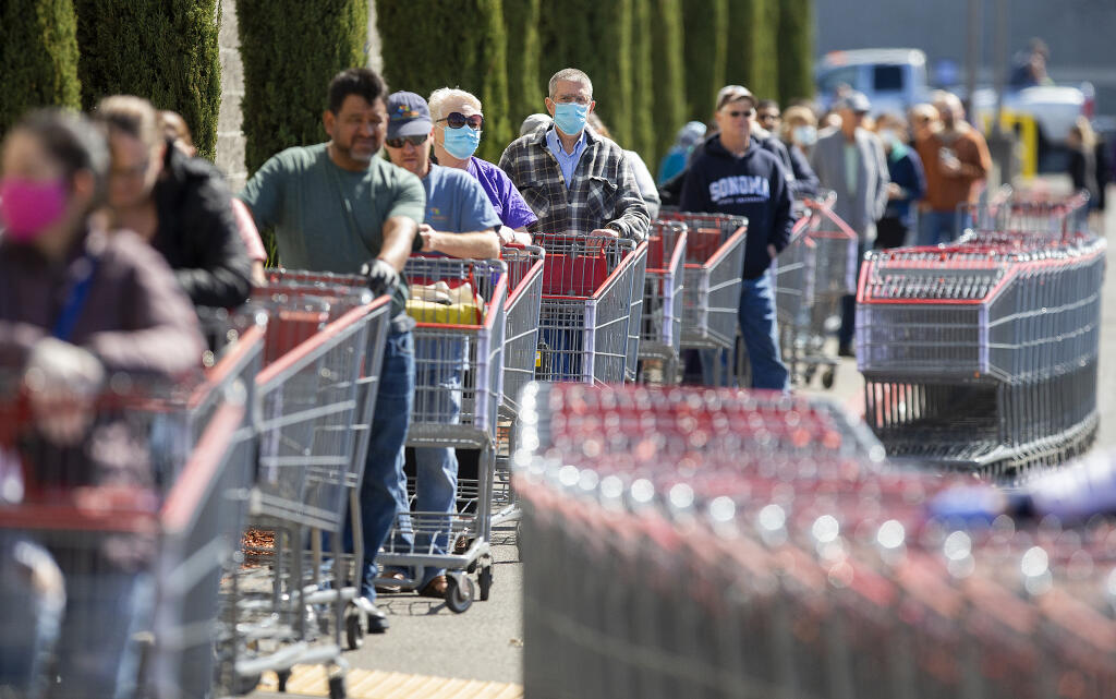 Shoppers wait in line spaced 6 feet apart at the Santa Rosa Costco on Friday, April 3, 2020. The line stretched around the building, and patrons waited up to 45 minutes to enter the store as personnel controlled the total number of people in the store at one time.   (John Burgess / The Press Democrat)