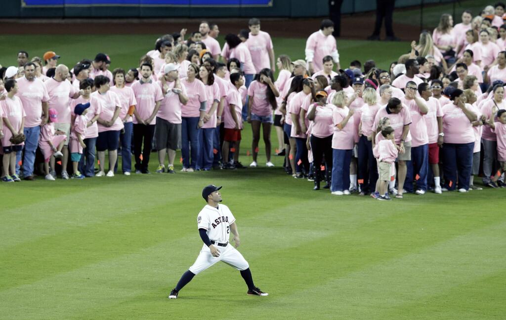Houston Astros' Jose Altuve (27) stretches as volunteers who have been affected by breast cancer fill a human pink ribbon for a breast cancer awareness tribute before the baseball game against the San Francisco Giants Tuesday, May 12, 2015, in Houston. (AP Photo/Pat Sullivan)