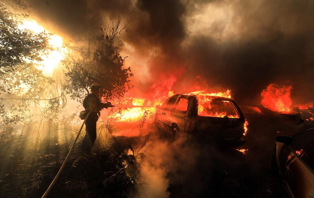 At the Upper Lake Rancheria, Santa Clara County firefighter Tyler James keeps a house and cars in check as he protects another structure as the Ranch fire rolls in to the outskirts of Upper Lake on Monday, July 30, 2018. (KENT PORTER/ PD)
