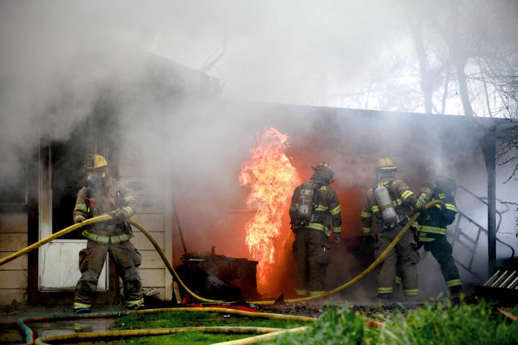 Firefighters work to extinguish a fire in a single-story home on Ramondo Drive just west of Santa Rosa on Wednesday, Feb.18, 2015. (BETH SCHLANKER/ PD)