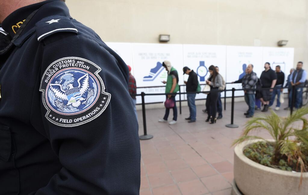 FILE - In this Dec. 10, 2015, file photo, pedestrians crossing from Mexico into the United States at the Otay Mesa Port of Entry wait in line in San Diego. The Trump administration is proposing rules that could deny green cards to immigrants if they use Medicaid, food stamps, housing vouchers and other forms of public assistance. The Department of Homeland Security said Saturday, Sept. 22, 2018, that current and past receipt of certain public benefits above thresholds will be considered 'a heavily weighed negative factor' in granting green cards as well as temporary visas. (AP Photo/Denis Poroy, File)