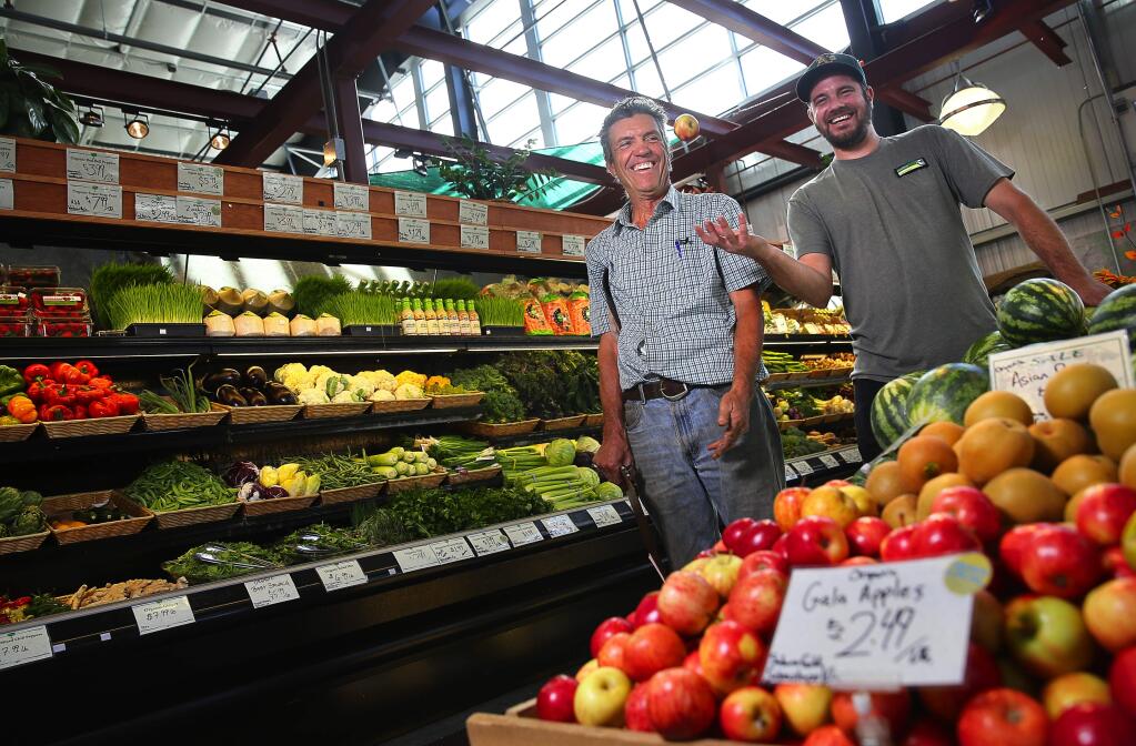 Geoffrey Power, right, produce manager at Community Market, in Sebastopol, features locally grown produce from farmers such as Johnnie Appleseed, owner of Appleseed Farms. (Christopher Chung/ The Press Democrat)