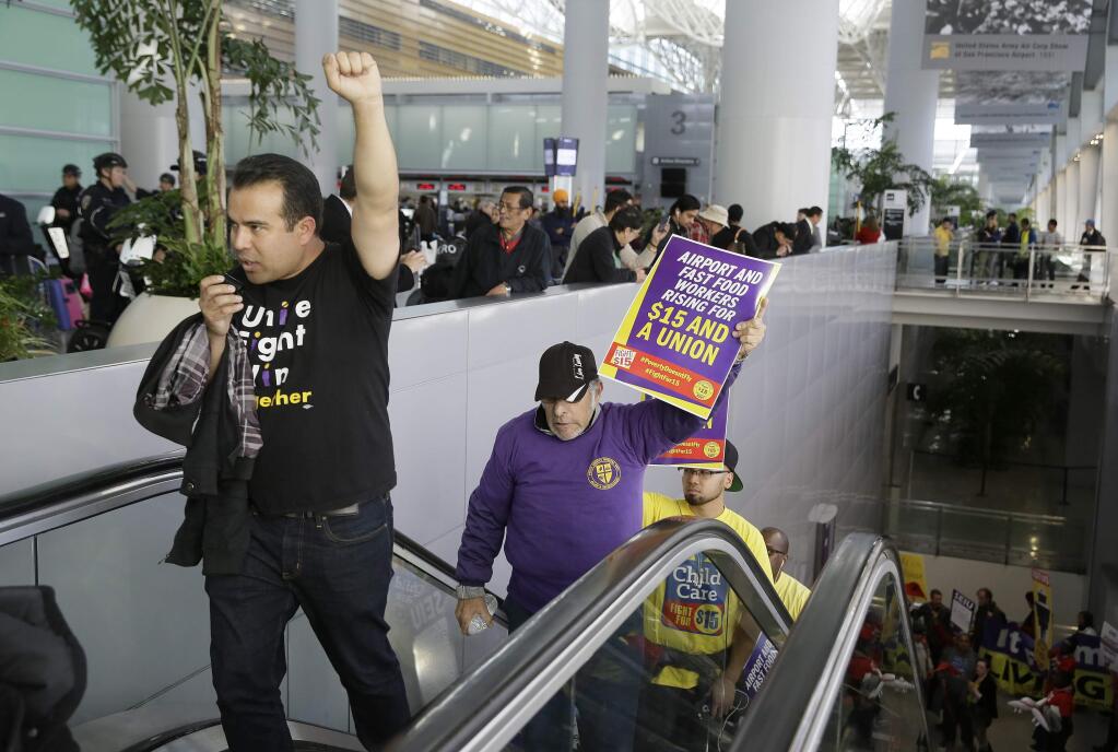 File - In this Nov. 29, 2016 file photo, workers march through the international terminal during a protest for a $15 minimum wage at San Francisco International Airport in San Francisco. The minimum wage in San Francisco increases to $15 an hour July 1, 2018, under a ballot measure approved by voters in 2014. San Francisco is the first major city in California to hit the magic $15 mark, but it won't be the last. (AP Photo/Eric Risberg, File)
