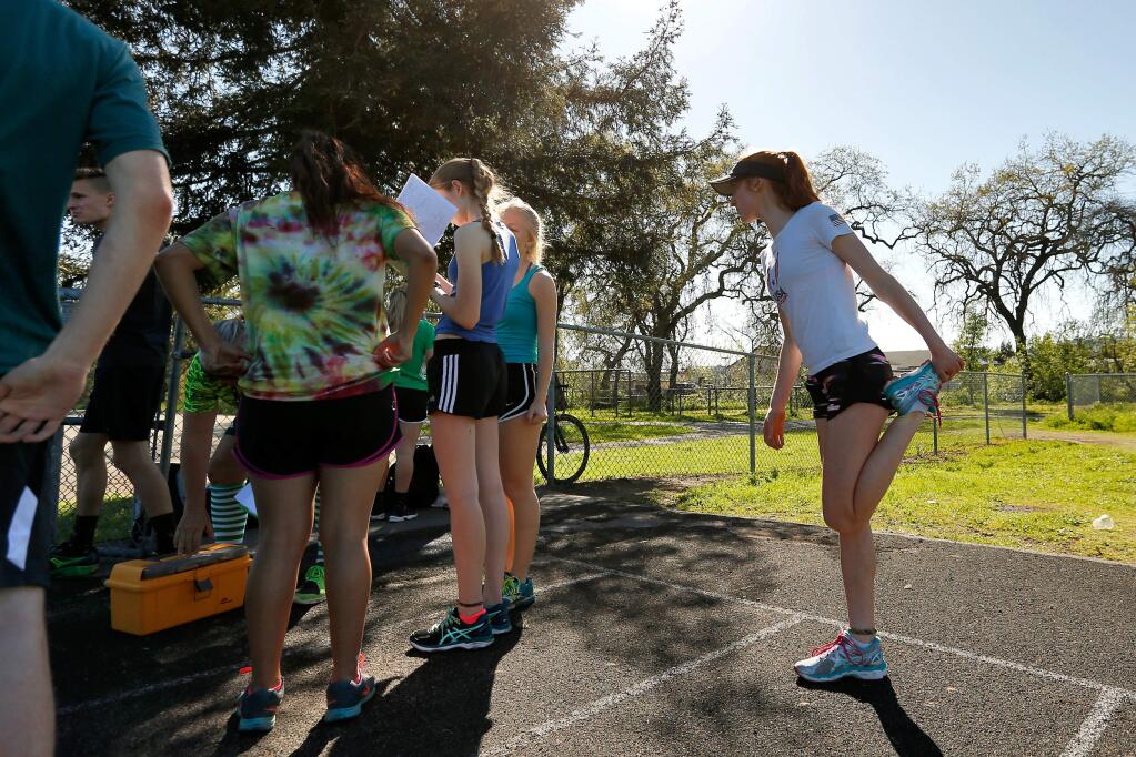 Sonoma Valley sophomore Amy Stanfield, right, stretches before going on a long-distance training run with her teammates during track and field team practice at Sonoma Valley High School on Thursday, March 17, 2016. (Alvin Jornada / The Press Democrat)