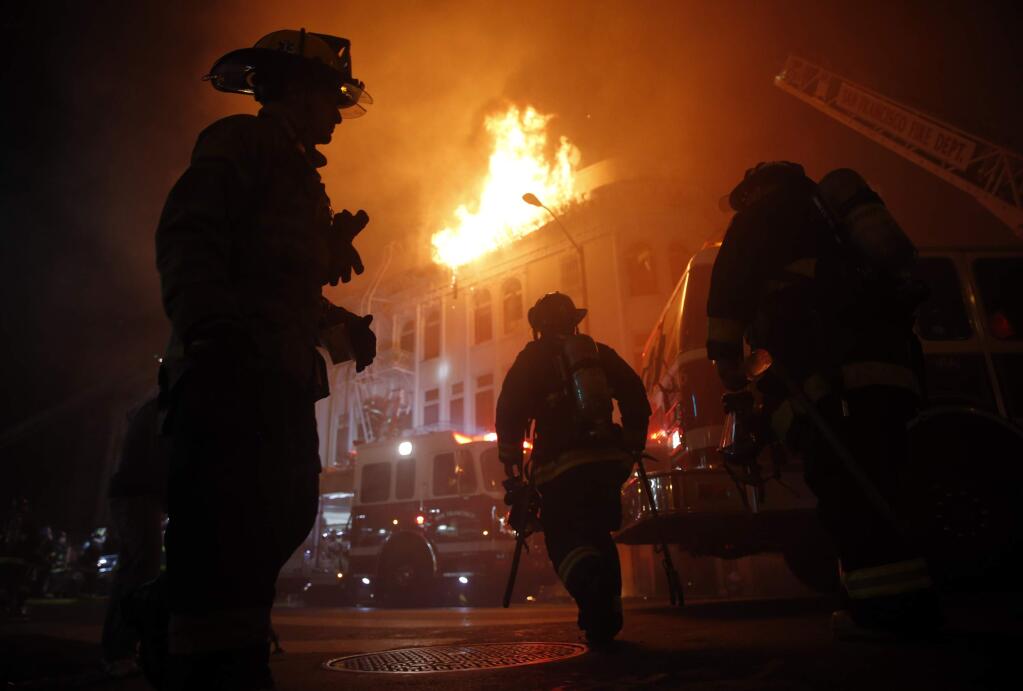 San Francisco Fire Department members fight a four-alarm fire at 22nd and Mission streets in San Francisco, Calif., on Wednesday, Jan. 28, 2015. Fire officials say one person is dead and six people have been injured in the massive, four-alarm fire in San Francisco's Mission District. (AP Photo/San Francisco Chronicle, Scott Strazzante)