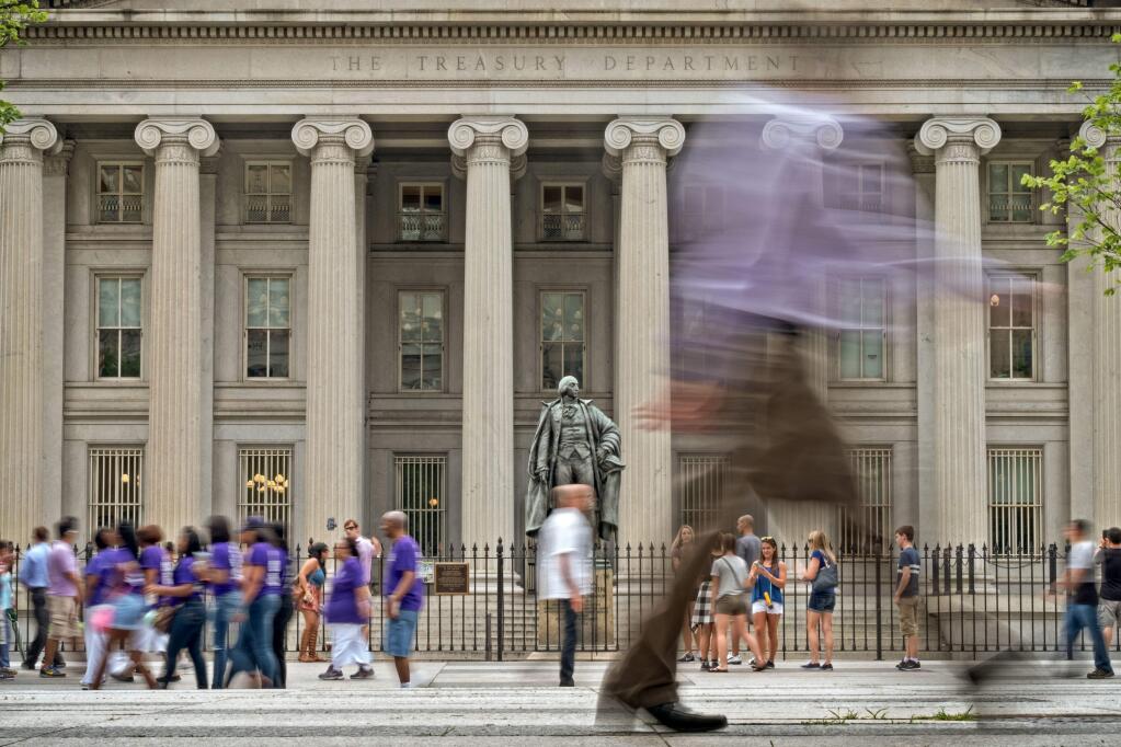 Pedestrians and tourists go about their usual lunchtime routine in front of the United States Treasury headquarters building in Washington, Friday, June 24, 2016, as the U.S. government and the financial markets analyze and react to Britain's vote to withdraw from the European Union. (AP Photo/J. David Ake)