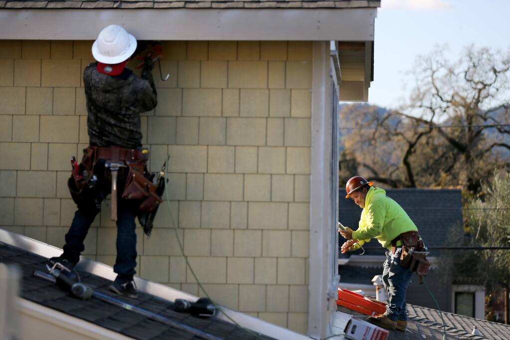 Contractors work to install fire resistant fiber-cement shingles on a new home on Lincoln Street being built by Hybridbuild Inc. in Healdsburg on Monday, Dec. 23, 2019. (BETH SCHLANKER/ The Press Democrat)