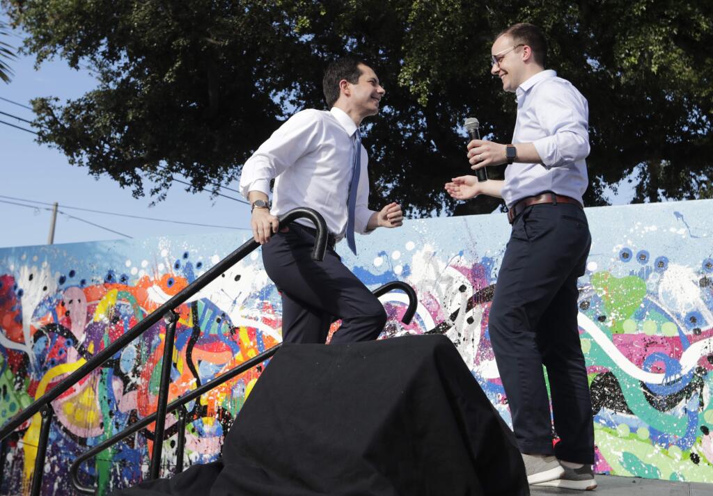 In this May 20, 2019, file photo, Democratic presidential candidate Pete Buttigieg, the mayor of South Bend, Ind., left, is introduced by his husband Chasten Buttigieg, right, during a fundraiser at the Wynwood Walls, in Miami. Buttigieg knows firsthand the burden of six-figure student loan debt. He and his husband have loans of more than $130,000, placing them in the ranks of the 43 million Americans who owe federal student debt.(AP Photo/Lynne Sladky, File)