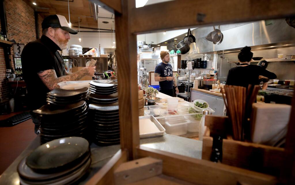 From left, co owner Matthew Williams and chef de cuisine's Joel Shaw and Geneva Melvy prepare take out orders at Ramen Gaijin, Tuesday, March 17, 2020 in Sebastopol. The restaurant is not open for dine in customers due to the coronavirus. (Kent Porter / The Press Democrat) 2020