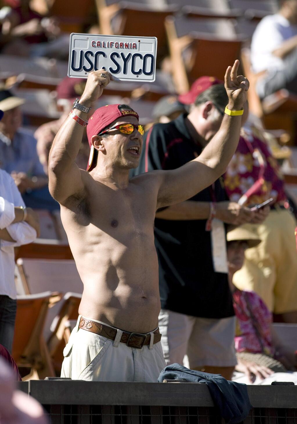 FILE - In this Sept. 2, 2010 file photo Roy Nwaisser, of Los Angeles, cheers during an NCAA college football game between the University of Southern California and Hawaii at Aloha Stadium in Honolulu. Nwaisser has four degrees from the University of Southern California and is a super fan of its storied football squad - he hasn't missed a home or away game in 27 years. But his devotion has been tested by a series of scandals culminating with the school's starring role in a massive college admissions bribery case that is the latest disgrace threatening to tarnish USC's hard-fought reputation as an academic, as well as athletic, powerhouse. (AP Photo/Eugene Tanner,File)