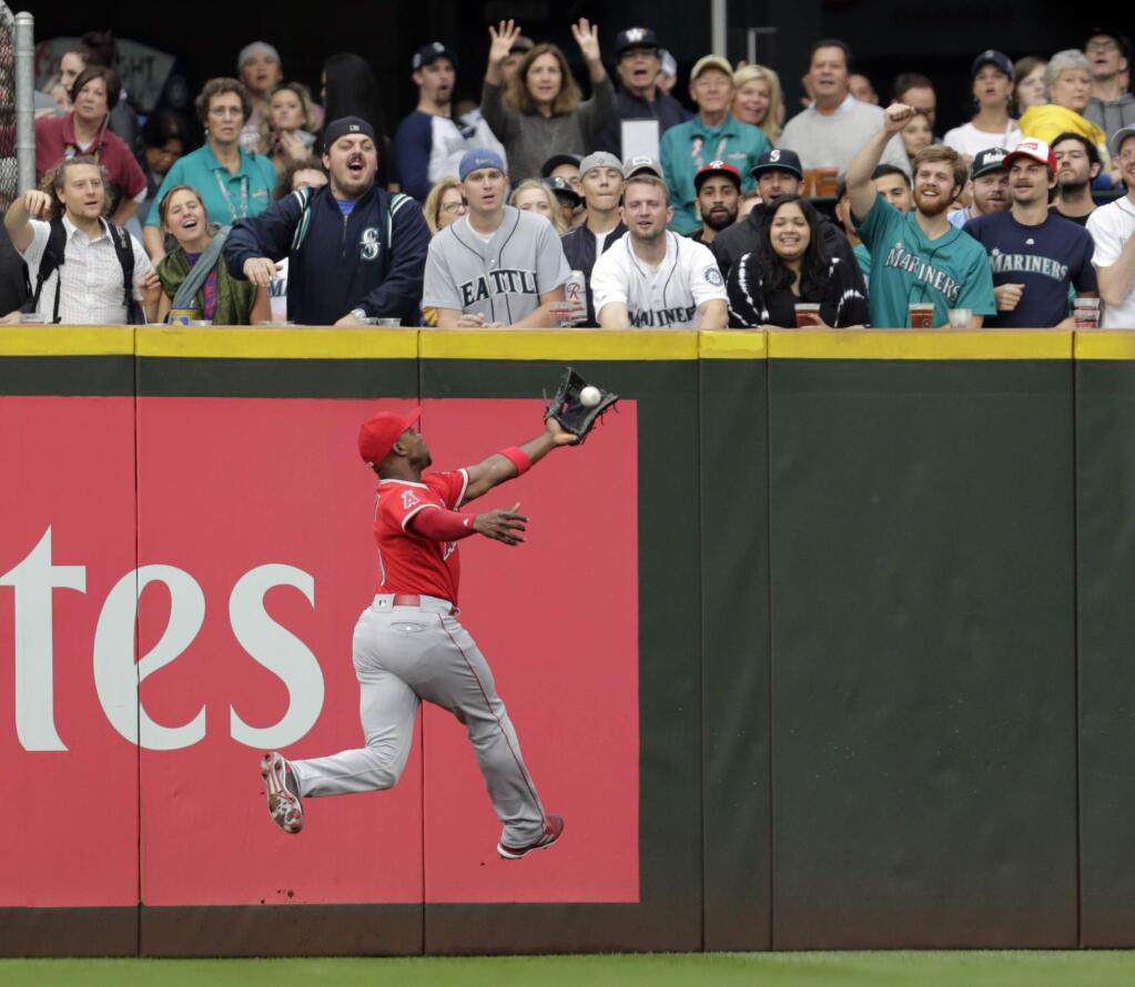 In this Sept. 9, 2017, file photo, Los Angeles Angels left fielder Justin Upton leaps to catch a fly ball hit by Seattle Mariners' Nelson Cruz. Outfielder Justin Upton is staying with the Angels, agreeing to a new five-year, $106 million contract. The Angels announced the deal Thursday, Nov. 2, 2017, with Upton, their late-season trade acquisition. (AP Photo/John Froschauer, File)