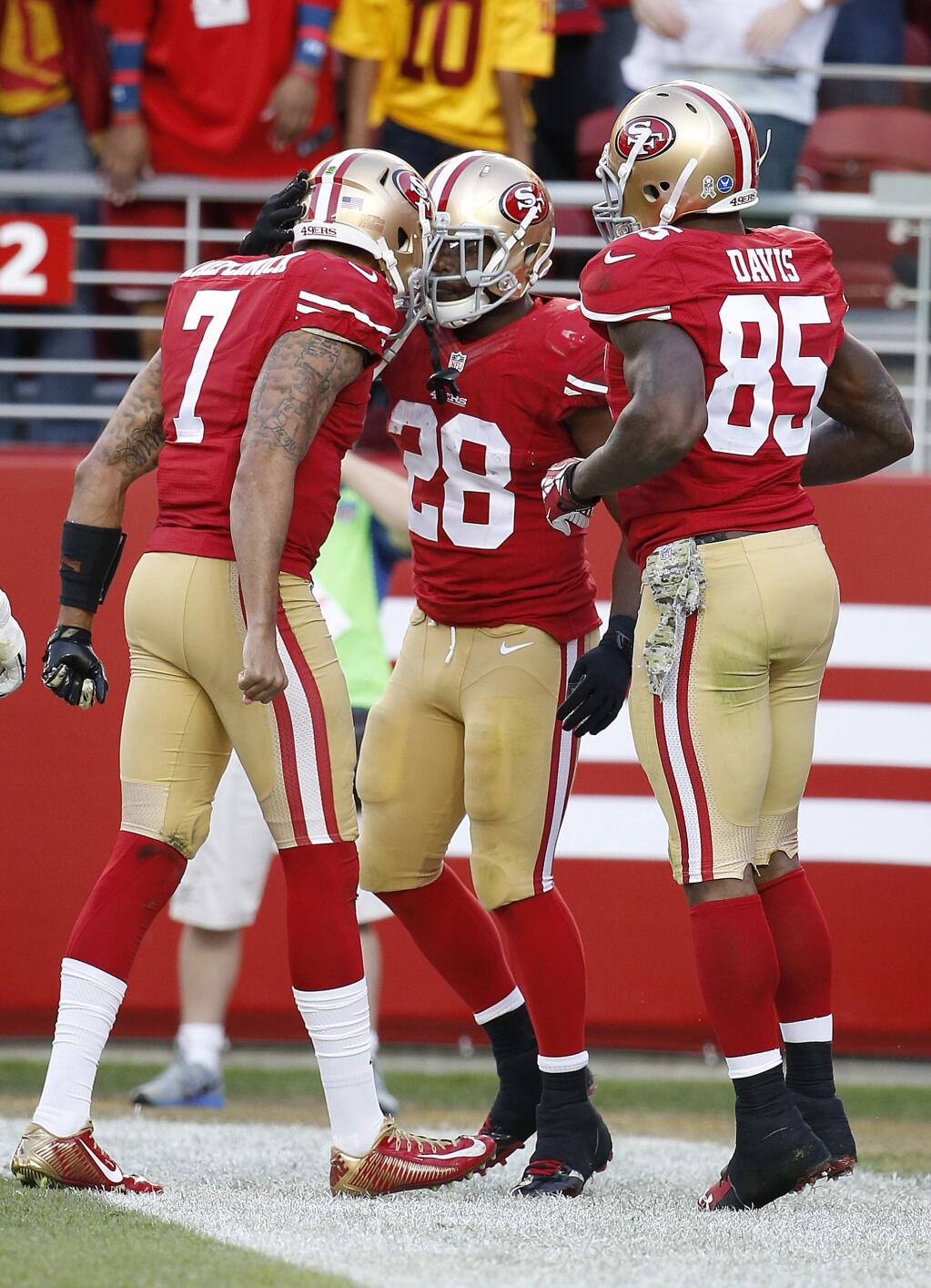 San Francisco 49ers running back Carlos Hyde, right, celebrates with quarterback Colin Kaepernick (7) and tight end Vernon Davis (85) after running for a 4-yard touchdown against the Washington Redskins during the fourth quarter of an NFL football game in Santa Clara, Calif., Sunday, Nov. 23, 2014. (AP Photo/Tony Avelar)