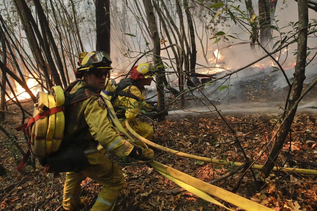 Firefighters put out a hot spot from a wildfire Thursday, Oct. 12, 2017, near Calistoga, Calif. Communities in wildfire-prone Northern California have an array of emergency systems designed to alert residents of danger: text messages, phone calls, emails and tweets. But after days of raging blazes left at least 23 dead, authorities said those methods will be assessed after some residents complained those warnings never got through. (AP Photo/Jae C. Hong)