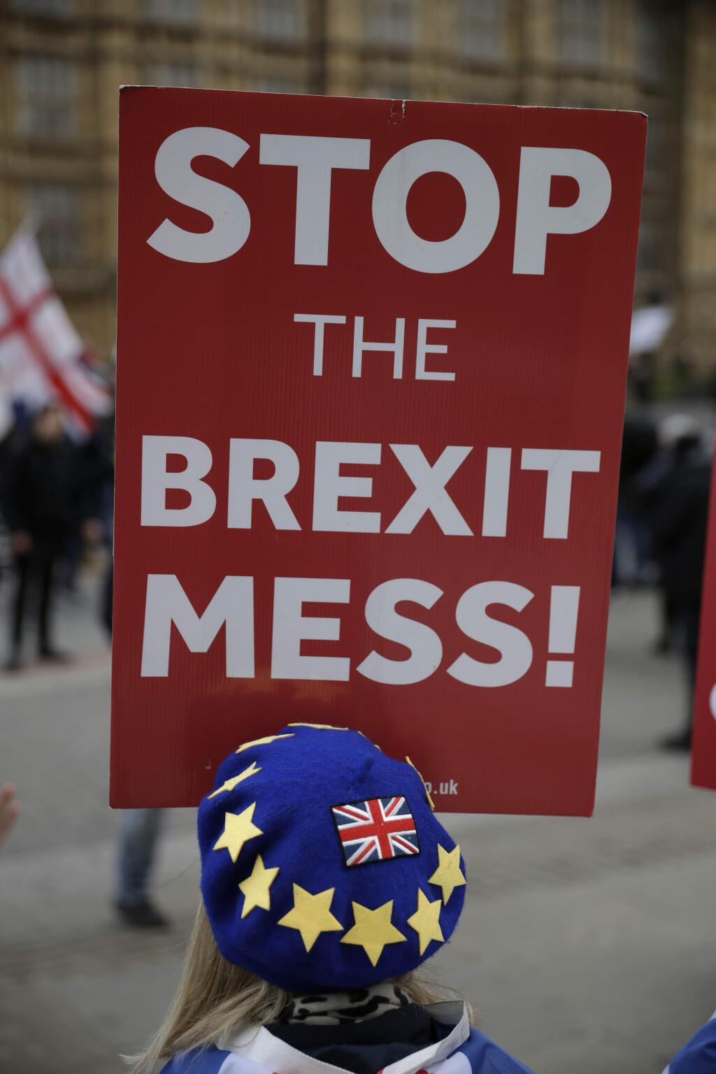 An anti-Brexit remain in the European Union supporter holds a placard as they demonstrate opposite the Houses of Parliament in London, Monday, Jan. 21, 2019. Prime Minister Theresa May says Britain is scrapping a fee it was due to charge European Union citizens applying to settle permanently in the U.K. after Brexit. (AP Photo/Matt Dunham)