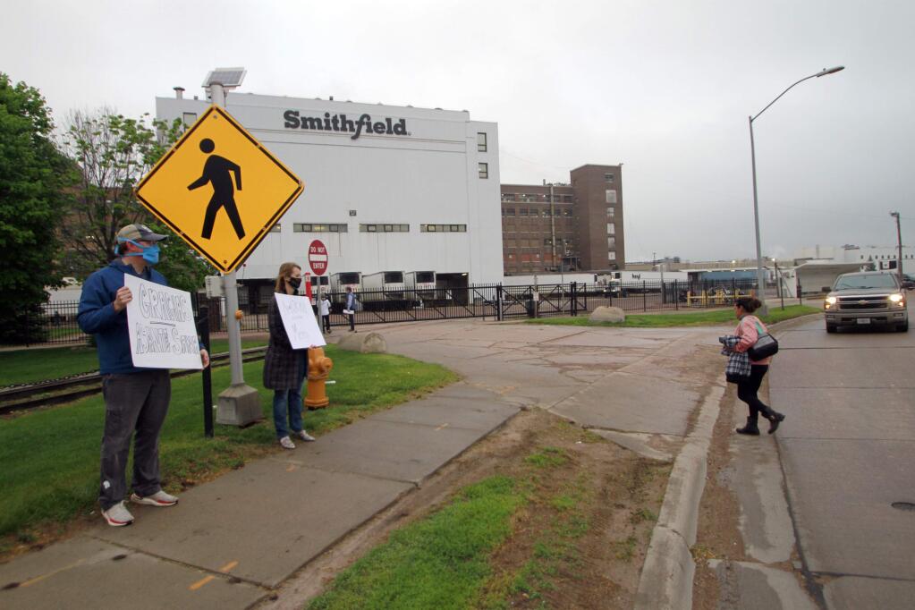 Residents cheered and held thank you signs to greet employees of a Smithfield pork processing plant as they begin their shift on Wednesday May 20, 2020 in Sioux Falls, S.D. Smithfield called many employees back to work after it closed the plant for more than three weeks because of a coronavirus outbreak that infected over 800 employees. (AP Photo/Stephen Groves)