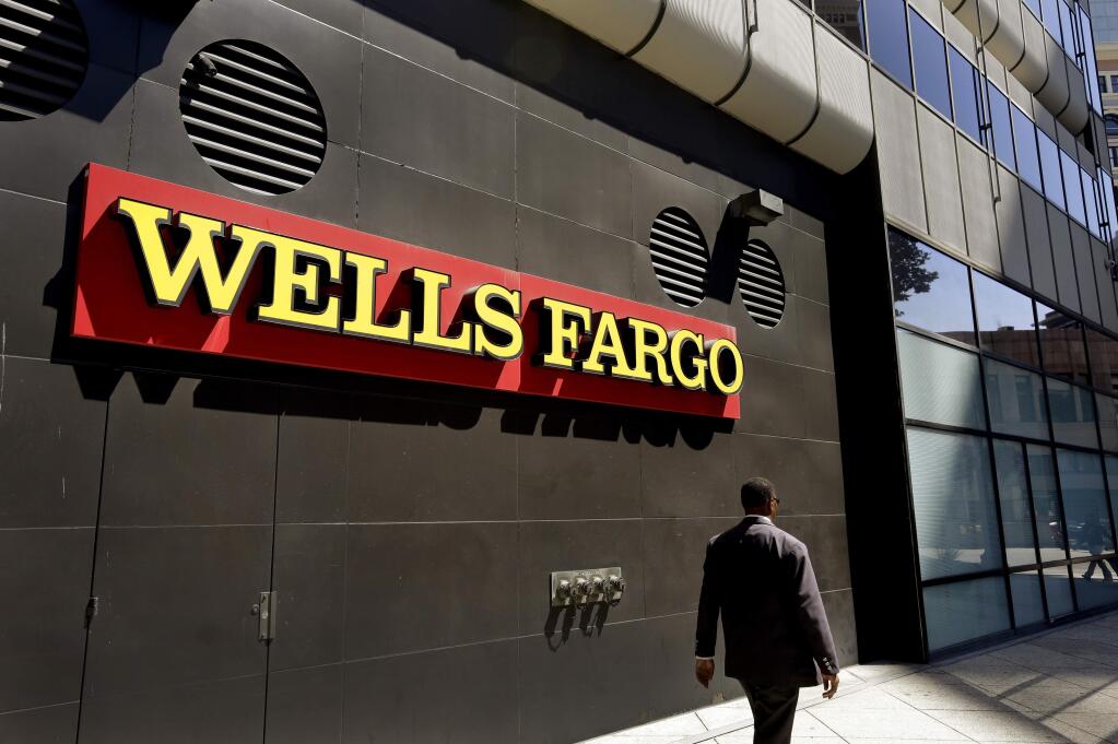 FILE - In this July 14, 2014 file photo, a man passes by a Wells Fargo bank in Oakland, Calif. (AP Photo/Ben Margot, File)