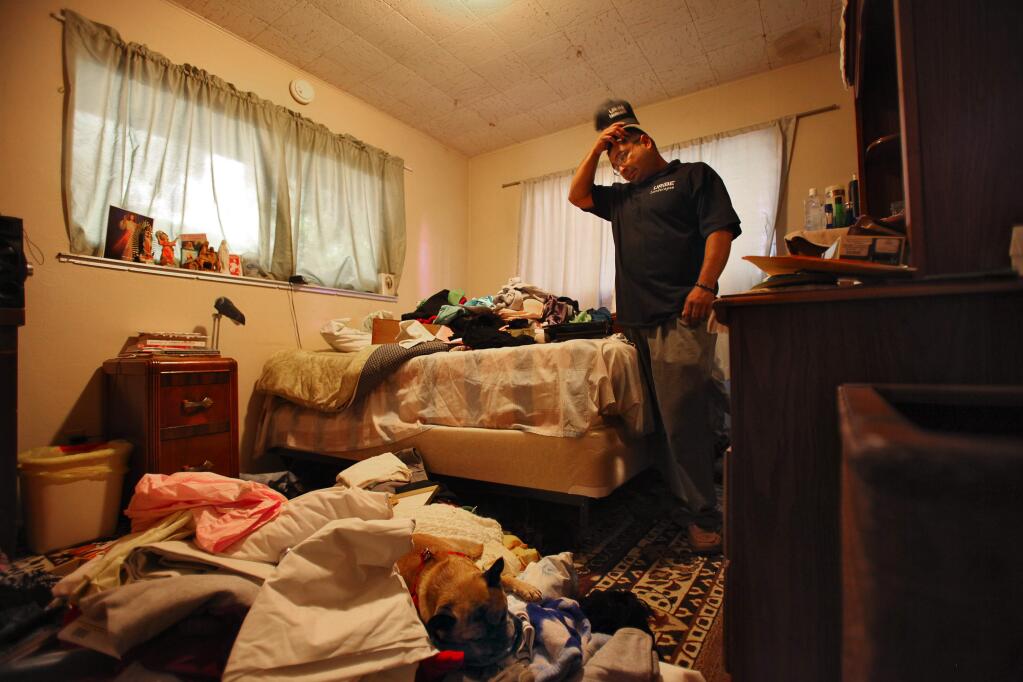 Mario Uribe looks over his mother's ransacked belongings in her room of his home, in the Whispering Pines area of Cobb, on Monday, September 28, 2015. Uribe returned to his home last Saturday, after the evacuation orders were lifted, to find that his home had been ransacked and looted.(Christopher Chung/ The Press Democrat)