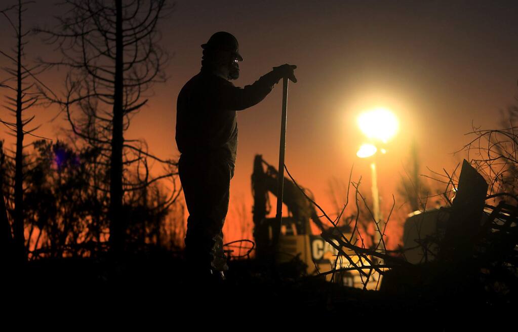 A crew from Argonaut Constructors of Santa Rosa work in to the night to clear debris from a razed home on Hillary Court in Coffey Park, Monday Nov. 6, 2017, one month after the Tubbs fire roared through Santa Rosa. (Kent Porter / The Press Democrat) 2017