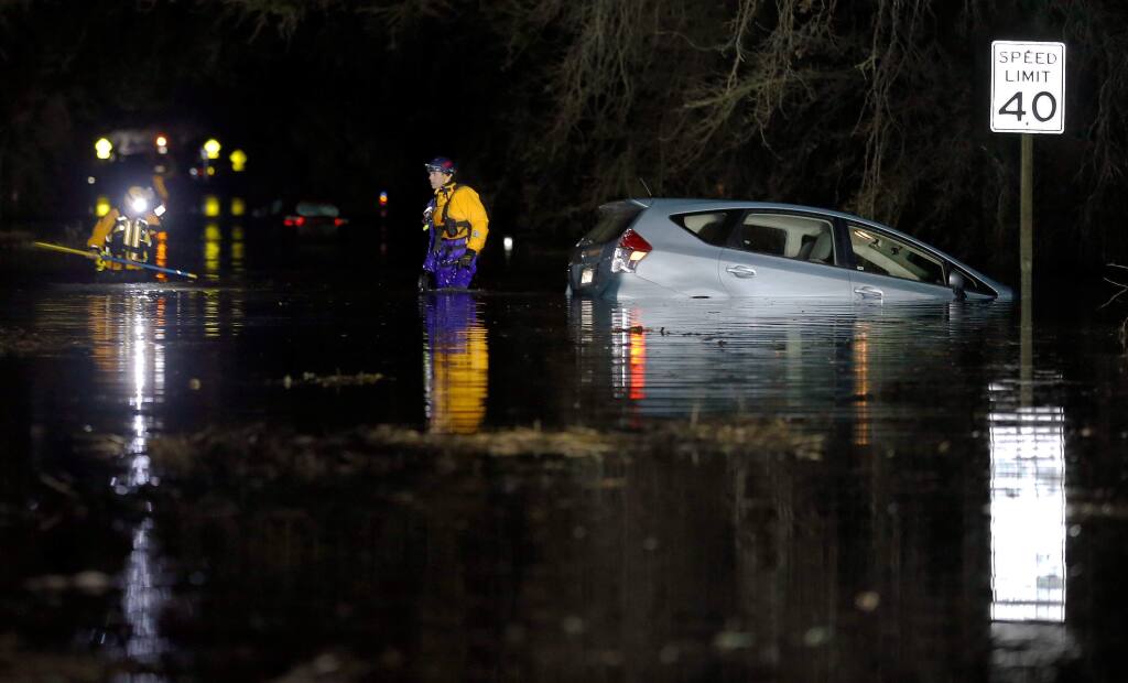 Santa Rosa Fire Department swift water rescue team members Capt. Wesley David, right, and firefighter Rob Giles check the area around a car stuck in the flood water on Willowside Road after rescuing its occupants, in Santa Rosa, California, on Wednesday, February 27, 2019. (Alvin Jornada / The Press Democrat)