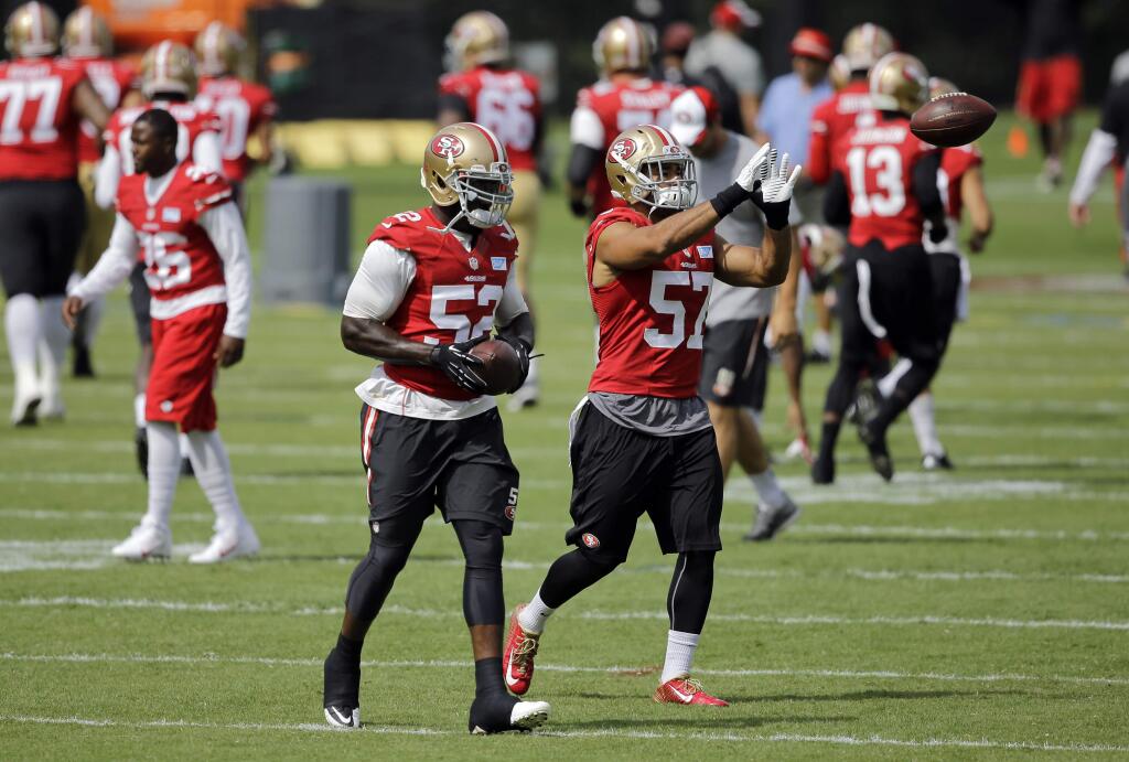 San Francisco 49ers linebacker Patrick Willis, left, walks alongside linebacker Michael Wilhoite as he prepares to catch a pass during an NFL football training camp practice, Monday, Aug. 11, 2014, in Owings Mills, Md. (AP Photo/Patrick Semansky)