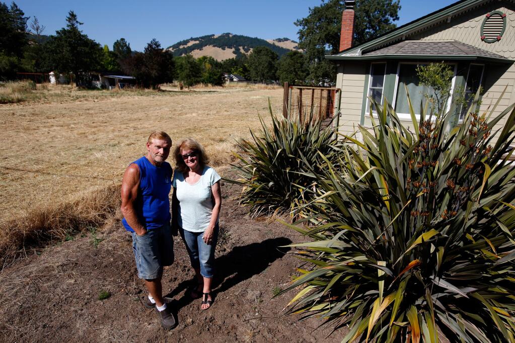 Michele and John Scudero pose for a photograph in front of their home, which is beside a vacant Santa Rosa city-owned property where a city well has been proposed to be built, in Santa Rosa, California on Wednesday, June 21, 2017. (Alvin Jornada / The Press Democrat)