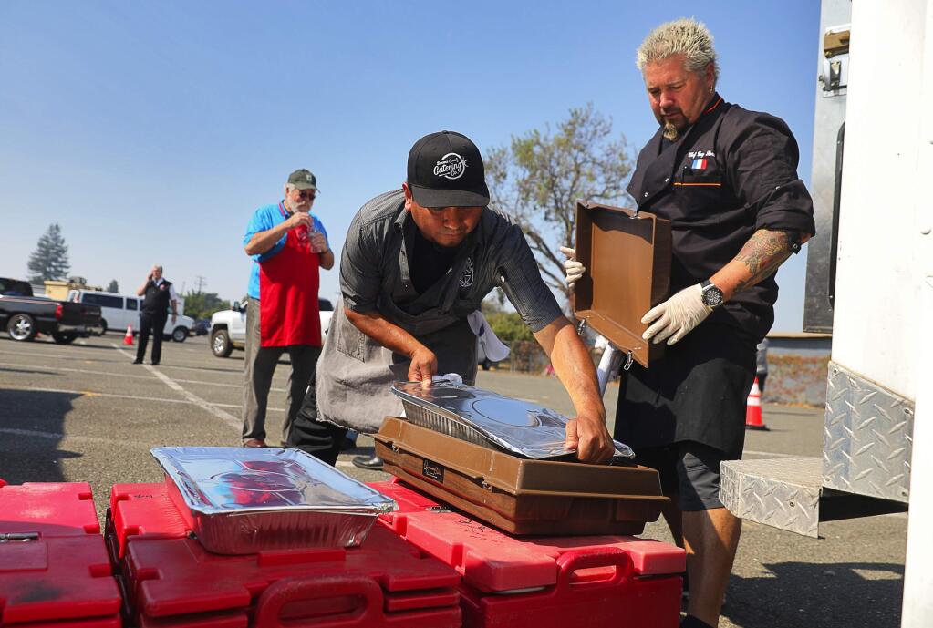 Celebrity chef Guy Fieri, right, and Cesar Orozco pack bins with food to be delivered to area evacuation centers by the Salvation Army, behind the Veterans Memorial Building in Santa Rosa on Thursday, Oct. 12, 2017. (Christopher Chung / The Press Democrat)
