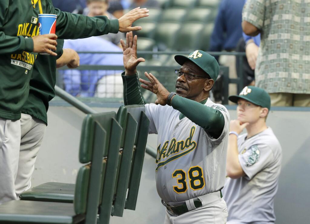 Oakland Athletics third base coach Ron Washington greets teammates in the dugout before the start of a baseball game against the Seattle Mariners, Monday, Aug. 24, 2015, in Seattle. The game was Washington's first since being named third base coach for the Athletics. (AP Photo/Ted S. Warren)