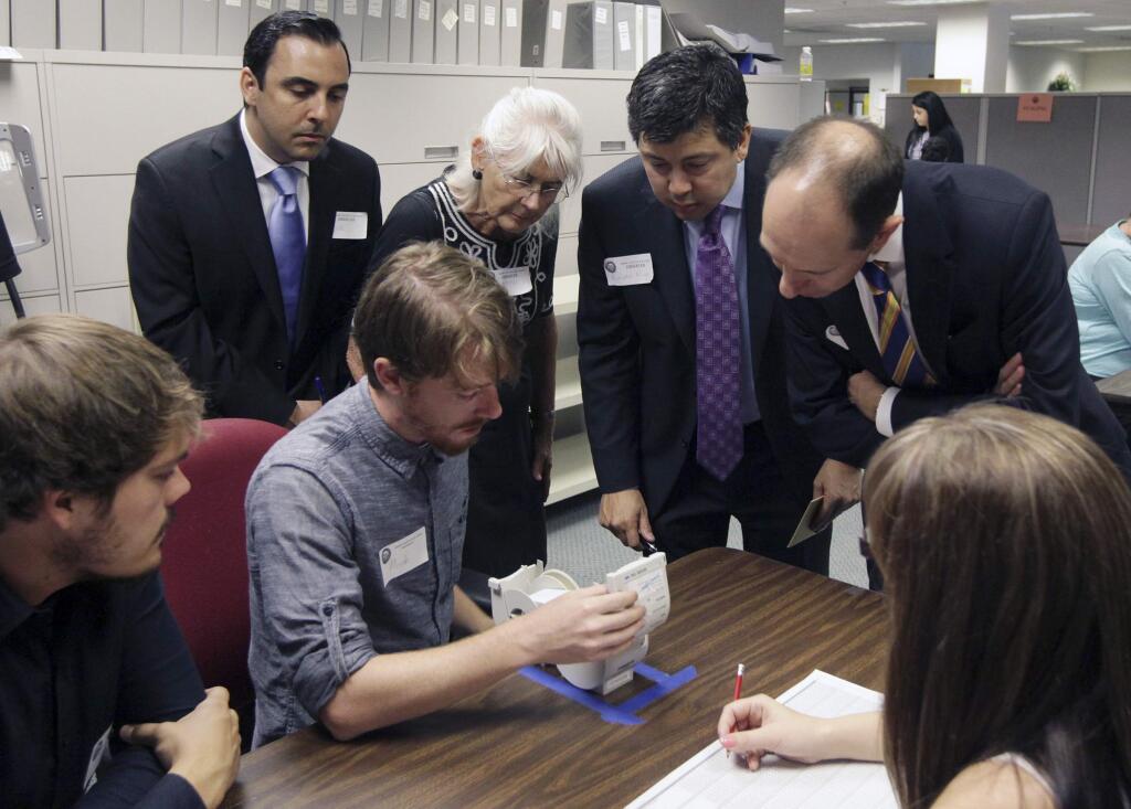 Observers watch as Micah Kagler of the Kern County elections division checks ballots in a recount of votes from the state controller race. (FELIX ADAMO / Bakersfield Californian)