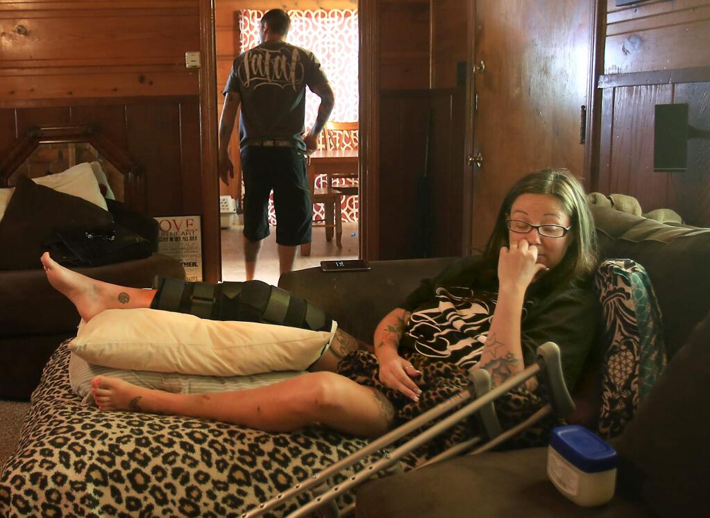 Heather Gladden rehabilitates at her home in Cloverdale, Tuesday April 19, 2016 after she fell about 500 feet when a zip line she was on outside Puerto Vallarta, Mexico failed, dropping her in to a canopy of trees. The accident occurred while she was on a cruise with her husband, Ryan, background. Her most serious injury was to her right knee and leg, which is in a brace. (Kent Porter / Press Democrat ) 2016