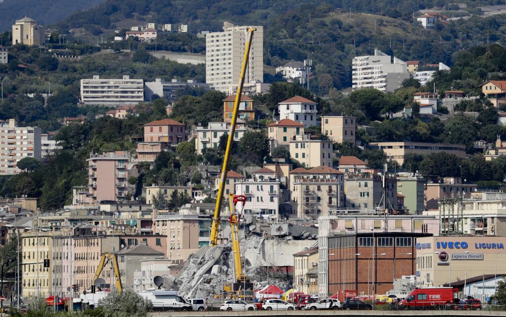 Firefighters remove debris of the collapsed Morandi highway bridge, in Genoa, Italy, Friday, Aug. 17, 2018. Excavators have begun clearing large sections of the collapsed highway bridge in the Italian city of Genoa in the search for people still missing three days after the deadly accident. (AP Photo/Gregorio Borgia)