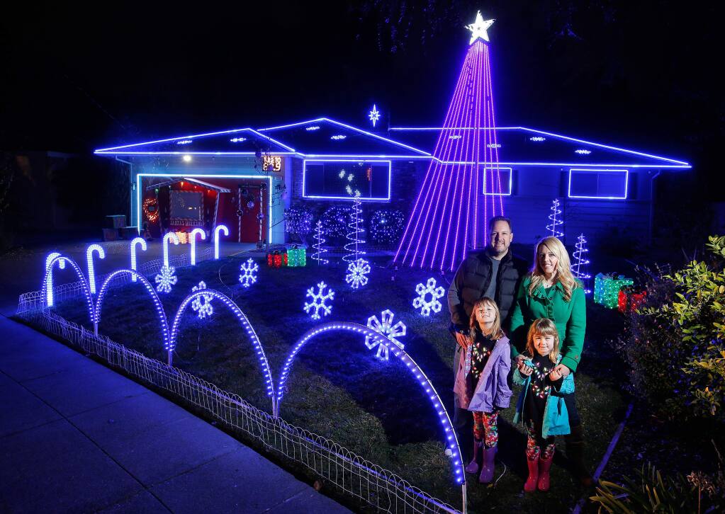 Nathan and Melissa Miller with their daughters Sawyer, 7, and Sloane, 6, stand in front of their home which is decorated with a high-tech holiday light display in Santa Rosa, California, on Tuesday, December 13, 2016. The Miller's holiday display features lights that are individually programmed to music, a digital banner that shows live text messages from visitors, and even a snow machine. (Alvin Jornada / The Press Democrat)