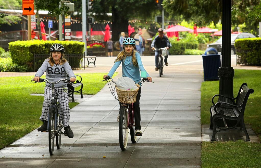 Julia Conley, 12, left, and Ella Holland, 12, rode their bikes to meet a friend at the town square in Healdsburg on Thursday, June 8, 2017. The town plans to launch a new bike sharing program for locals in a few months. (John Burgess/The Press Democrat)