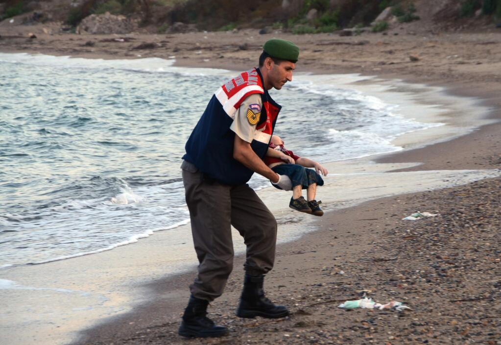 A paramilitary police officer carries the lifeless body of Aylan Kurdi, 3, after a number of migrants died and a smaller number were reported missing after boats carrying them to the Greek island of Kos capsized, near the Turkish resort of Bodrum early Wednesday, Sept. 2, 2015. (AP Photo/DHA)