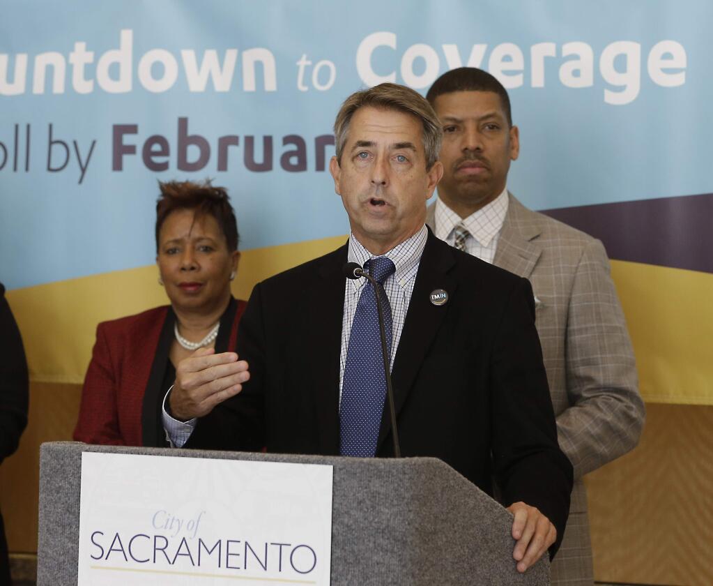 In this photo taken Feb. 9, 2015, Peter Lee, center, executive director of Covered California, the state's health insurance marketplace, discusses health insurance sign ups at a news conference with Sacramento Mayor Kevin Johnson, right, in Sacramento Calif. (AP Photo/Rich Pedroncelli)