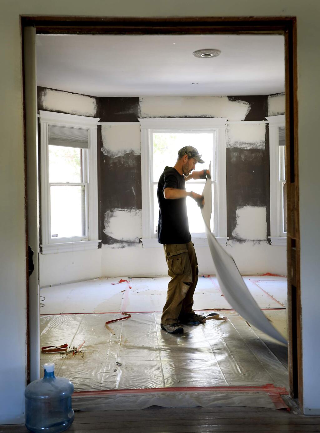 Steve King of Leff Construction Design Build pulls up thermo ply, used to protect wood flooring as a house is remodeled in Petaluma, Wednesday August 23, 2017. (Kent Porter / The Press Democrat) 2017