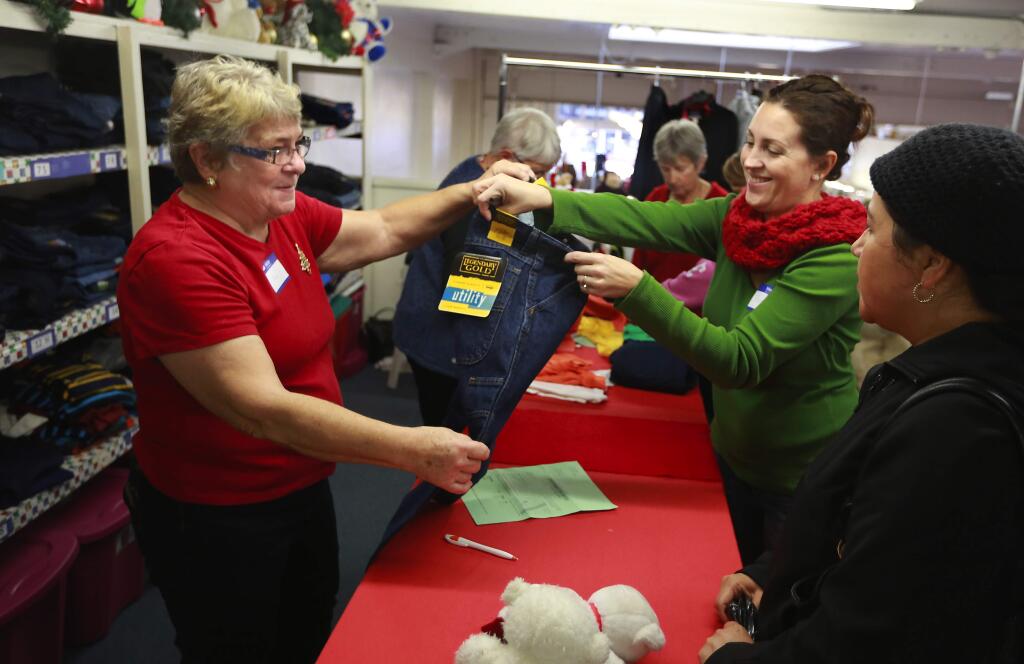 Jen Howard, left, and Amy Davidge help Maria Solis find clothing for her four children at the Welfare League Christmas Unlimited toy and clothing giveaway in Santa Rosa on Wednesday, December 10, 2014. (photo by John Burgess/The Press Democrat)