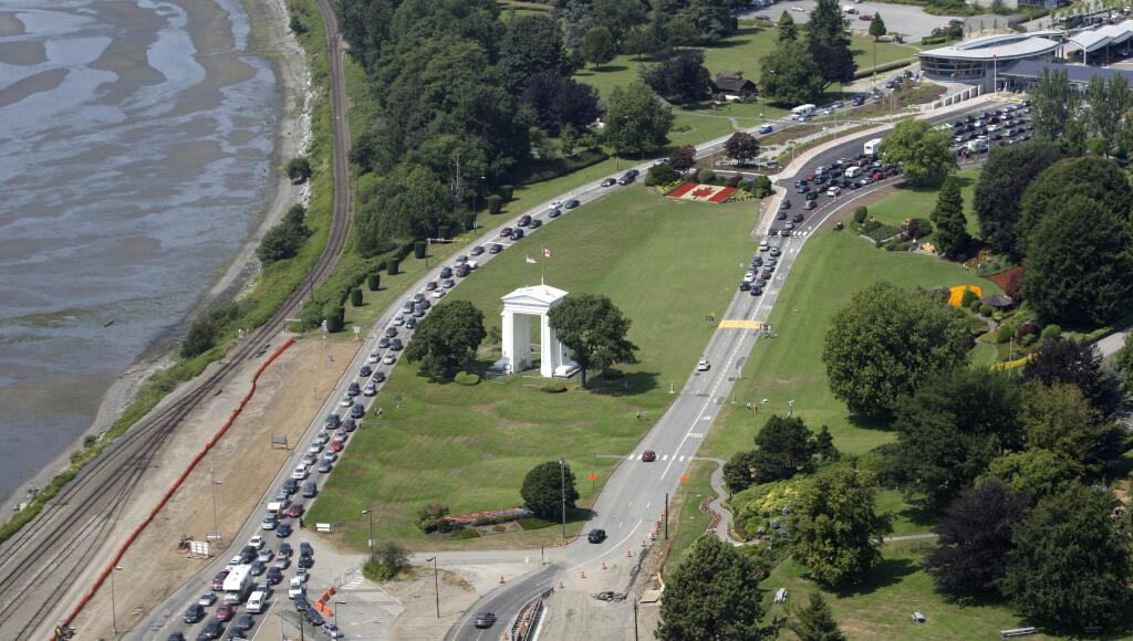 FILE - In this July 24, 2009 file photo, cars line-up heading into the United States at left and into Canada at right adjacent to Boundary Bay at a border crossing at Blaine, Wash. A 19-year-old woman who traveled from France to Canada to visit her mother in British Columbia says U.S. officials detained her for two weeks after she accidentally crossed the border while jogging. Cedella Roman tells the Canadian Broadcast Co. that two U.S. Customs and Border Protection agents apprehended her on May 21, 2018 on a beach south of White Rock, British Columbia. Roman says she didn't have identification and was transferred to the Tacoma Northwest Detention Center run by the Department of Homeland Security. (AP Photo/Elaine Thompson)