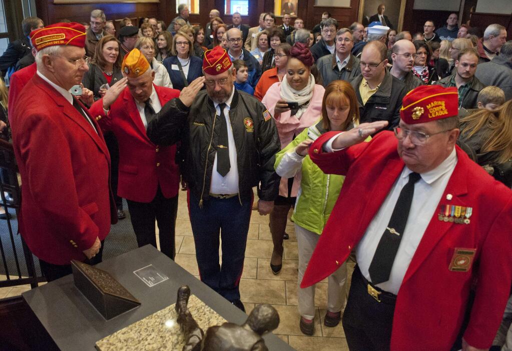 Members of the Marine Corps League salute the sculpture made to honor of Dennis Lobbezoo, a Grand Rapids man who was killed in Vietnam on Tuesday, Nov. 11, 2014 in Grand Rapids, Mich. The sculpture was created by Dr. Edward Byrd and is on display at the Steelcase Library lobby at the Grand Valley State University in downtown campus in Grand Rapids. (AP Photo/The Grand Rapids Press, Chris Clark)