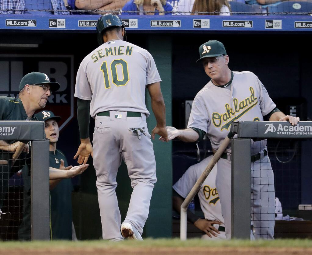 Oakland Athletics' Marcus Semien is welcomed back to the dugout after scoring on a single by Bruce Maxwell during the third inning of a baseball game against the Kansas City Royals on Wednesday, Sept. 14, 2016, in Kansas City, Mo. (AP Photo/Charlie Riedel)
